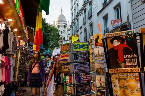 Street with souvenir shops on Montmartre with the Basilica Sacre-Coeur in the background