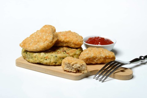 Meat substitute on wooden board and tray with ketchup