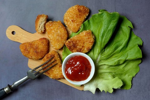 Meat substitute on wooden board and tray with ketchup