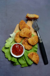 Meat substitute on wooden board and tray with ketchup