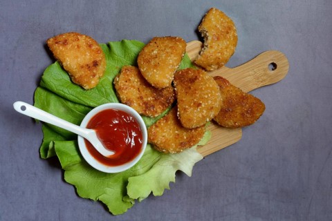 Meat substitute on wooden board and tray with ketchup