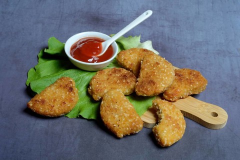 Meat substitute on wooden board and tray with ketchup
