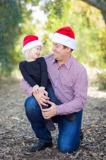 Portrait of father and daughter wearing santa hats outdoors