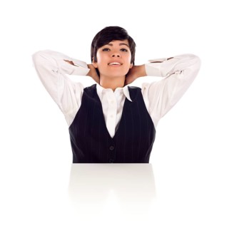 Attractive smiling mixed-race young adult female sitting at white table with hands behind her head isolated on a white background
