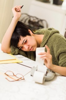 Multi-ethnic young woman agonizing over financial calculations in her kitchen