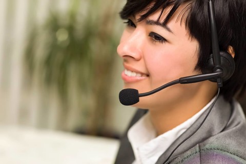 Attractive young mixed-race woman smiles wearing headset in office setting