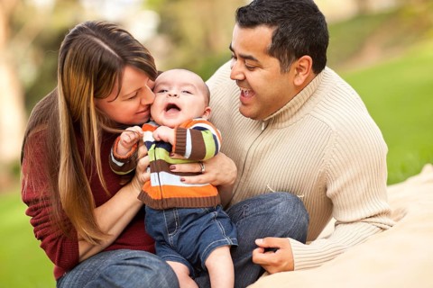 Happy mixed-race parents playing with their giggling son