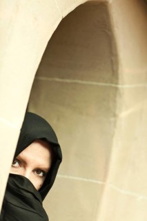 Cautious islamic woman in a window pane wearing traditional burqa or niqab