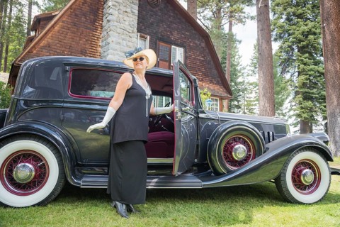 Attractive young woman in twenties outfit near antique automobile