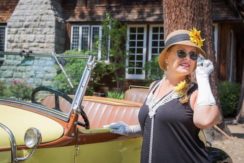 Attractive young woman in twenties outfit near antique automobile