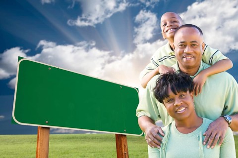 Attractive african american family in front of blank green road sign ready for your own message