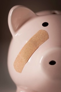 Piggy bank with bandage on face on dramatic gradated background