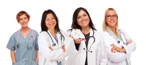 Attractive hispanic female doctor or nurse holding out baby shoes and support staff behind isolated on a white background
