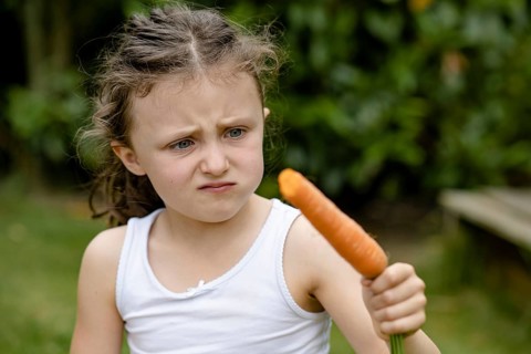 Girl with carrot turns up her nose