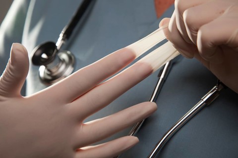 Abstract image of doctor taking off latex surgical gloves