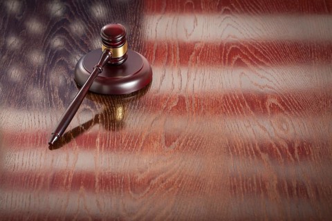 Wooden gavel resting on american flag reflecting table