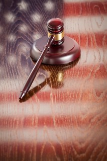Wooden gavel resting on american flag reflecting table