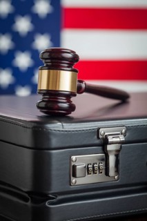 Leather briefcase and gavel resting on table with american flag behind