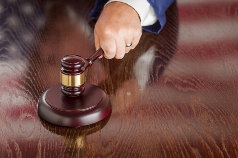 Judge slams his gavel and american flag table reflection