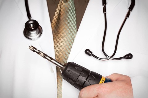Doctor with stethoscope holding A very big drill
