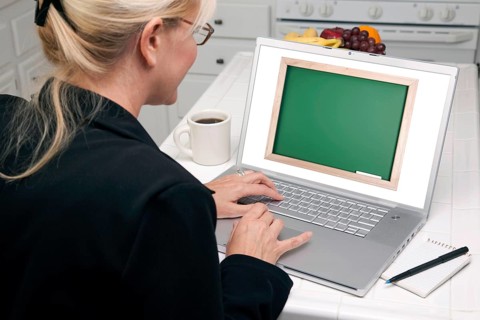 Woman in kitchen using laptop with blank chalkboard ready for you own message. screen can be easily used for your own message or picture. picture on screen is my copyright as well