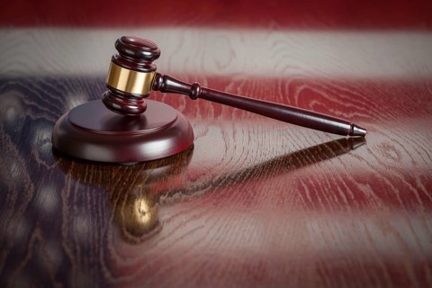 Wooden gavel resting on american flag reflecting table