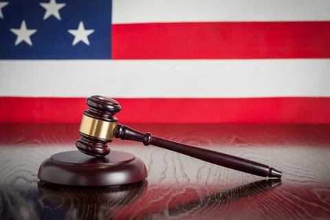 Wooden gavel resting on american flag reflecting table