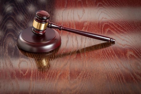 Wooden gavel resting on american flag reflecting table