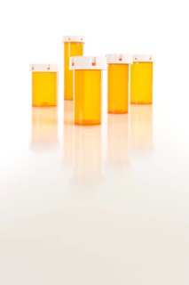 Several different sized empty medicine bottles on reflective surface