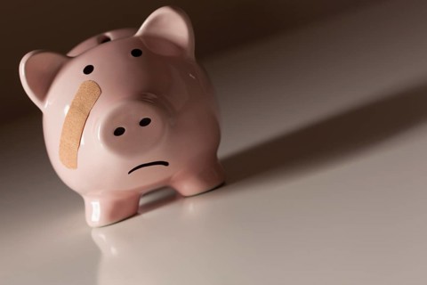 Piggy bank with bandage on face on dramatic gradated background