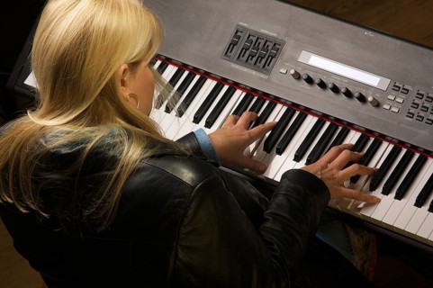 Female musician sings while playing digital piano