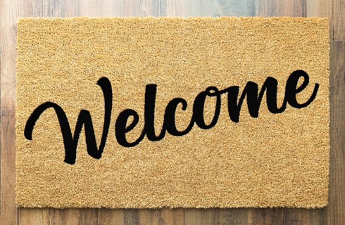 Tan welcome mat on wood floor background
