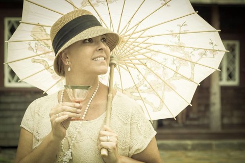 Beautiful 1920s dressed girl with parasol and glass of wine portrait