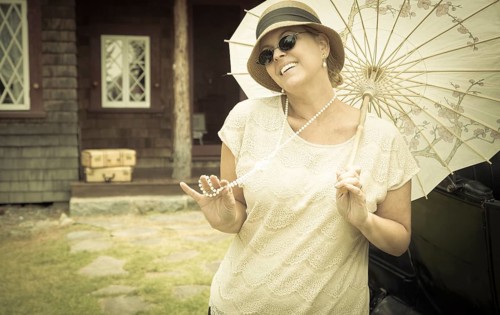 Beautiful 1920s dressed girl with parasol near vintage car