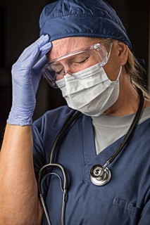 Grimacing female doctor or nurse wearing protective facial wear and surgical gloves