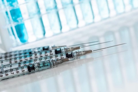 Abstract of scientific needle syringes and test tubes containing blue chemical in rack