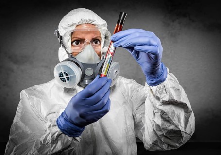 Female doctor or nurse in hazmat gear holding positive coronavirus test tube