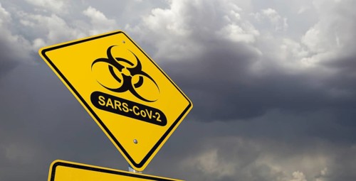 Bio-hazard symbol with sars-cov-2 coronaravirus yellow road sign against ominous stormy cloudy sky