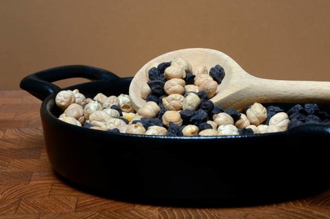 Light and black chickpeas in pot with cooking spoon