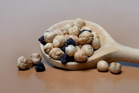 Light and black chickpeas in cooking spoon