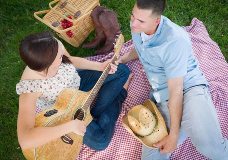 Happy mixed-race couple at the park playing guitar and singing songs