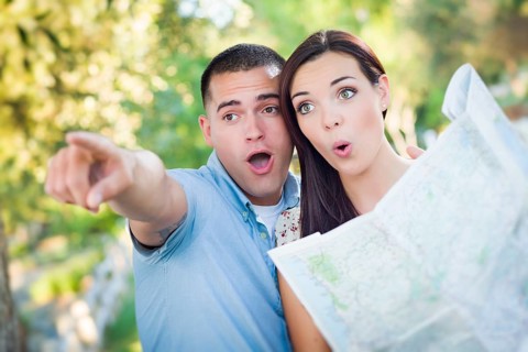 Happy mixed-race couple looking over A map and the sites outside together