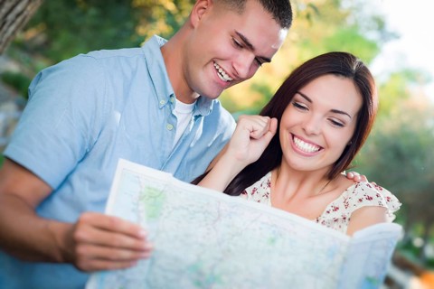 Happy mixed-race couple looking over A map outside together