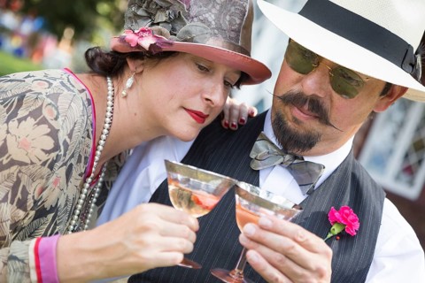 Attractive mixed-race couple dressed in 1920's era fashion sipping champagne