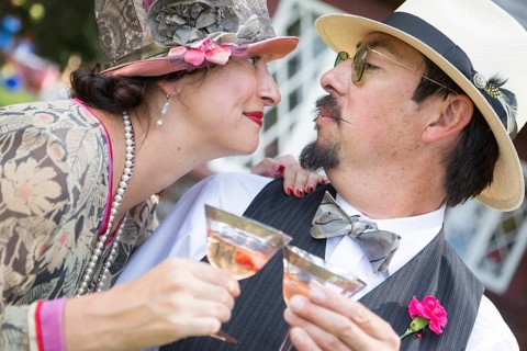Attractive mixed-race couple dressed in 1920's era fashion sipping champagne