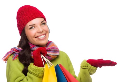 Beautiful mixed-race woman wearing winter hat and gloves isolated on a white background gesturing with her hand to the side