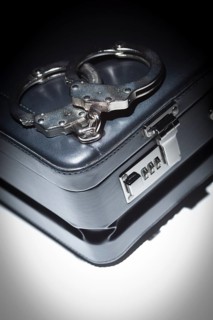 Pair of handcuffs and briefcase under spot light abstract