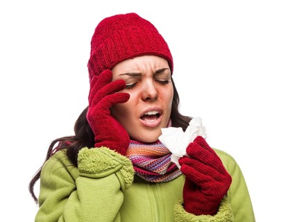 Sick mixed-race woman wearing winter hat and gloves blowing her sore nose with a tissue isolated on white background
