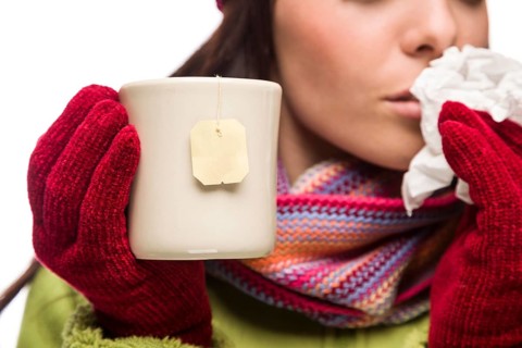 Young sick woman with tissue holding cup with blank tea bag hanging