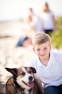 Handsome young boy playing with his dog at the beach